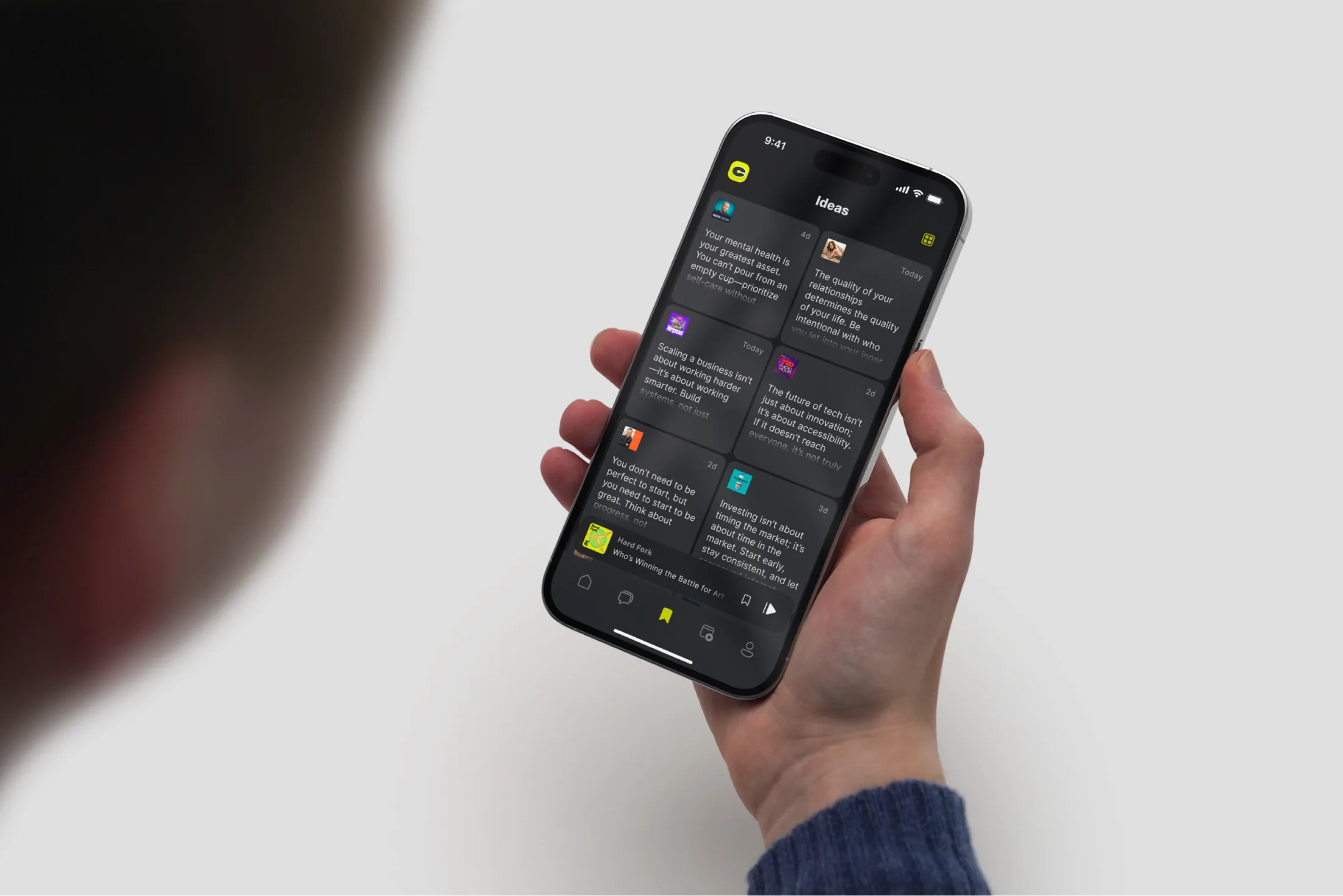 CueUp Ideas on an iPhone held in hand, a grid of saved quotes