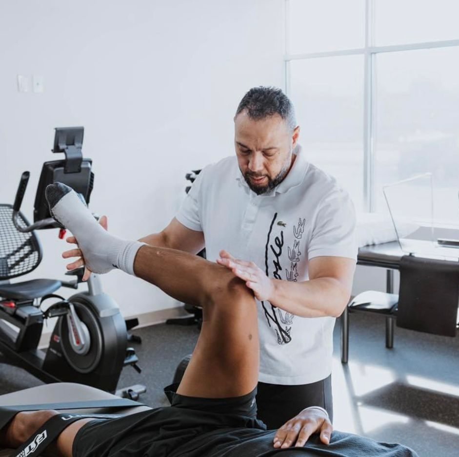 Ghassan treating a patient's raised leg in a bright clinic
