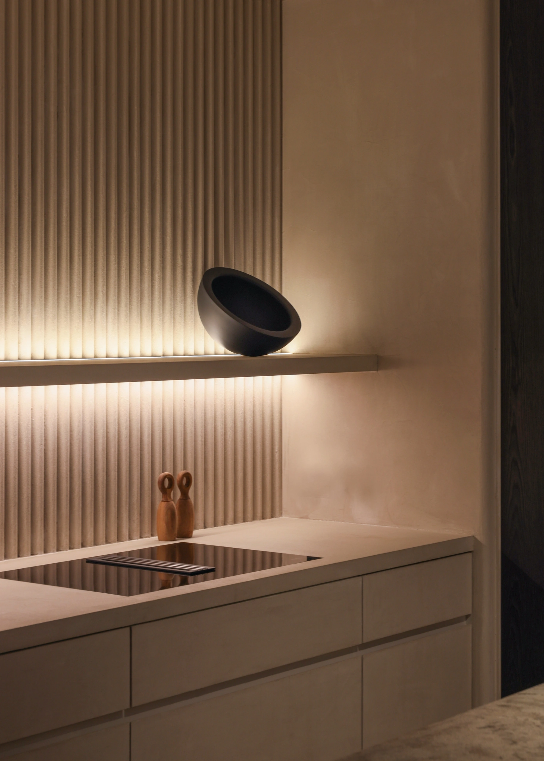 Sculptural interior kitchen staging with fluted plaster backdrop and ambient lighting
